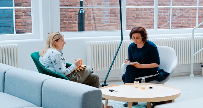 Photos showing two people talking around a table